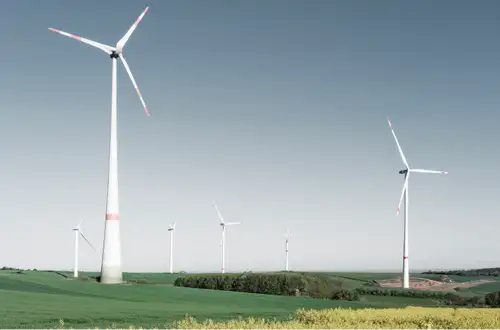 Windräder auf einem Hügel im Saarland, umgeben von Feldern.