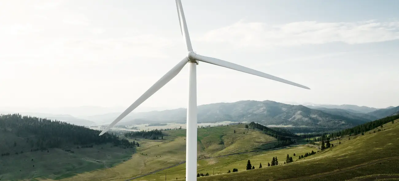 Von Windkraft profitieren: Unser Ratgeber für Grundeigentümer Windrad ragt aus nebliger, hügeliger Landschaft hervor.