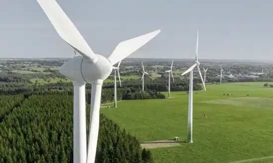 Fünf gute Gründe für ein Windrad auf eigenem Grundstück Luftaufnahme eines Windparks mit vielen Windrädern in weiter Landschaft.