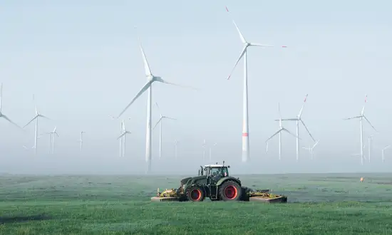 Ein Traktor fährt auf einem Acker für Windrad verpachten
