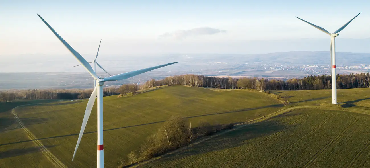 Successful Wind Projects Facilitated by Caeli Wind Wind turbines on a green hill.
