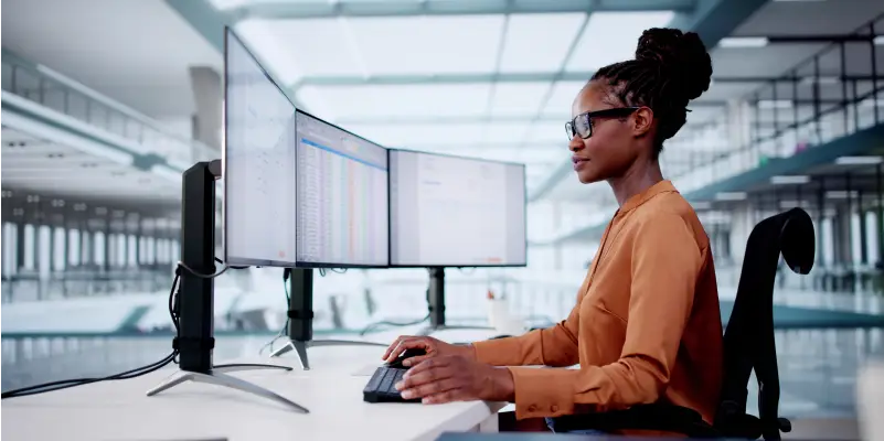 Submit Your Bid Woman working on a laptop in a modern office.