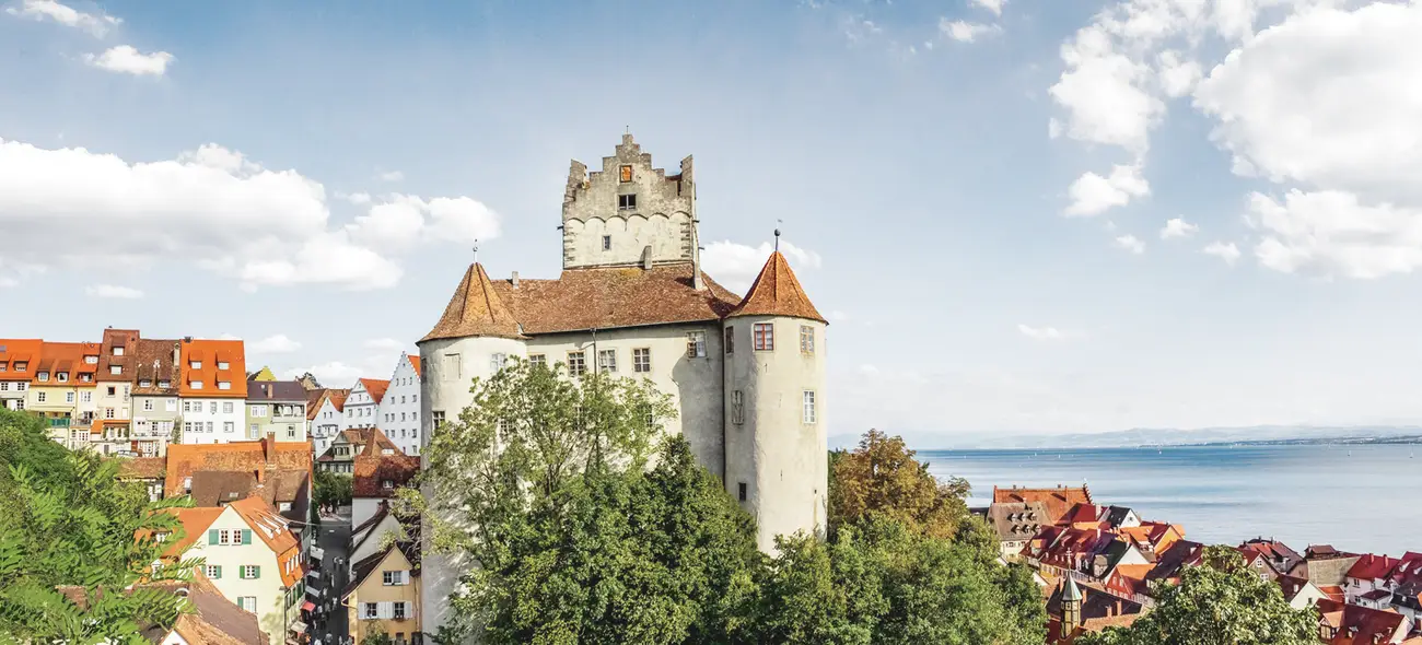 Windenergie in Baden-Württemberg Großes Schloss auf einem Hügel in Baden-Württemberg, umgeben von Bäumen und einem Fluss.