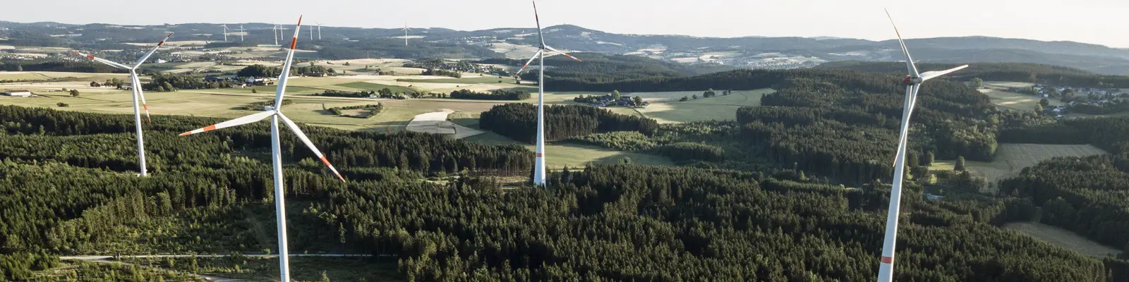 Luftaufnahme eines Windparks mit mehreren Windrädern über Wald- und Agrarlandschaft. Luftaufnahme eines Windparks mit mehreren Windrädern über Wald- und Agrarlandschaft.