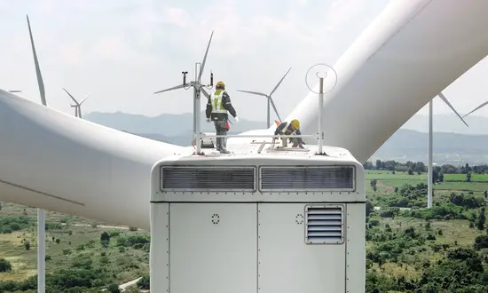 Erfolgsfaktor Repowering: Warum die Weiterentwicklung bestehender Windparks für Projektentwickler so attraktiv ist Techniker stehen auf einer Windkraftanlage und inspizieren einen weiteren Windpark in hügeliger Landschaft.